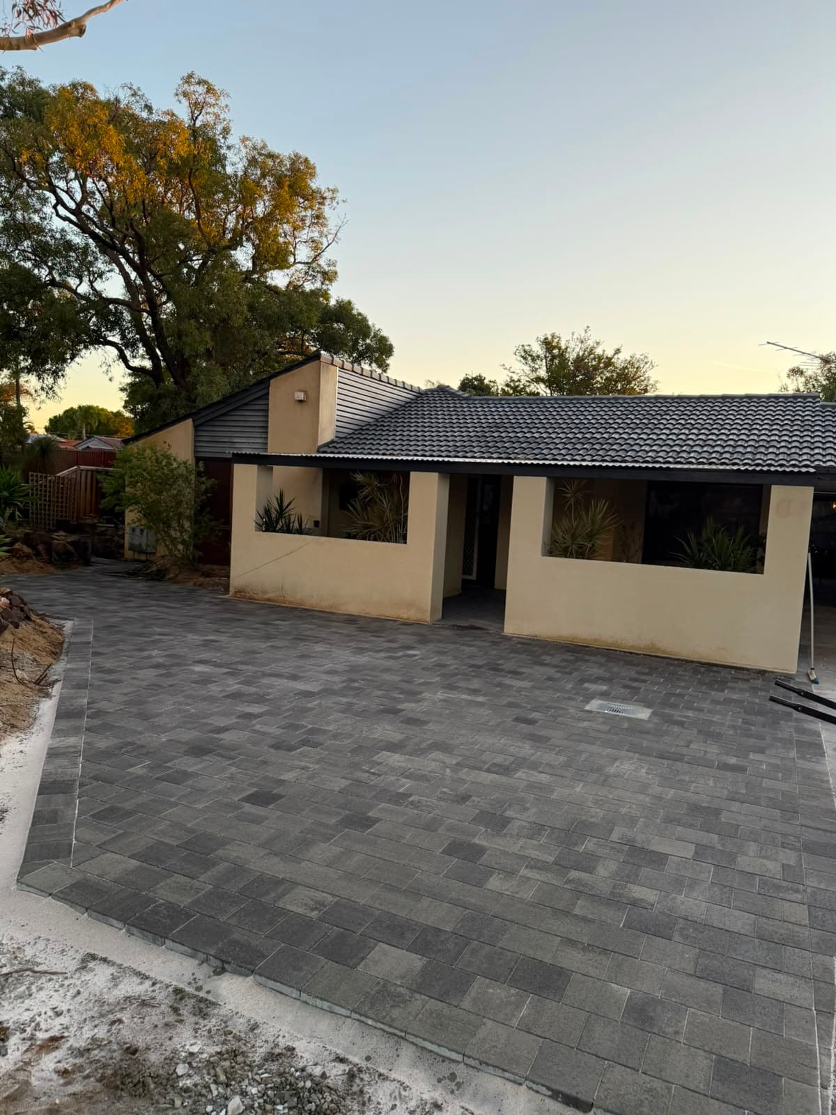 Grey concrete pavers laid across a driveway and forecourt at dusk, Perth