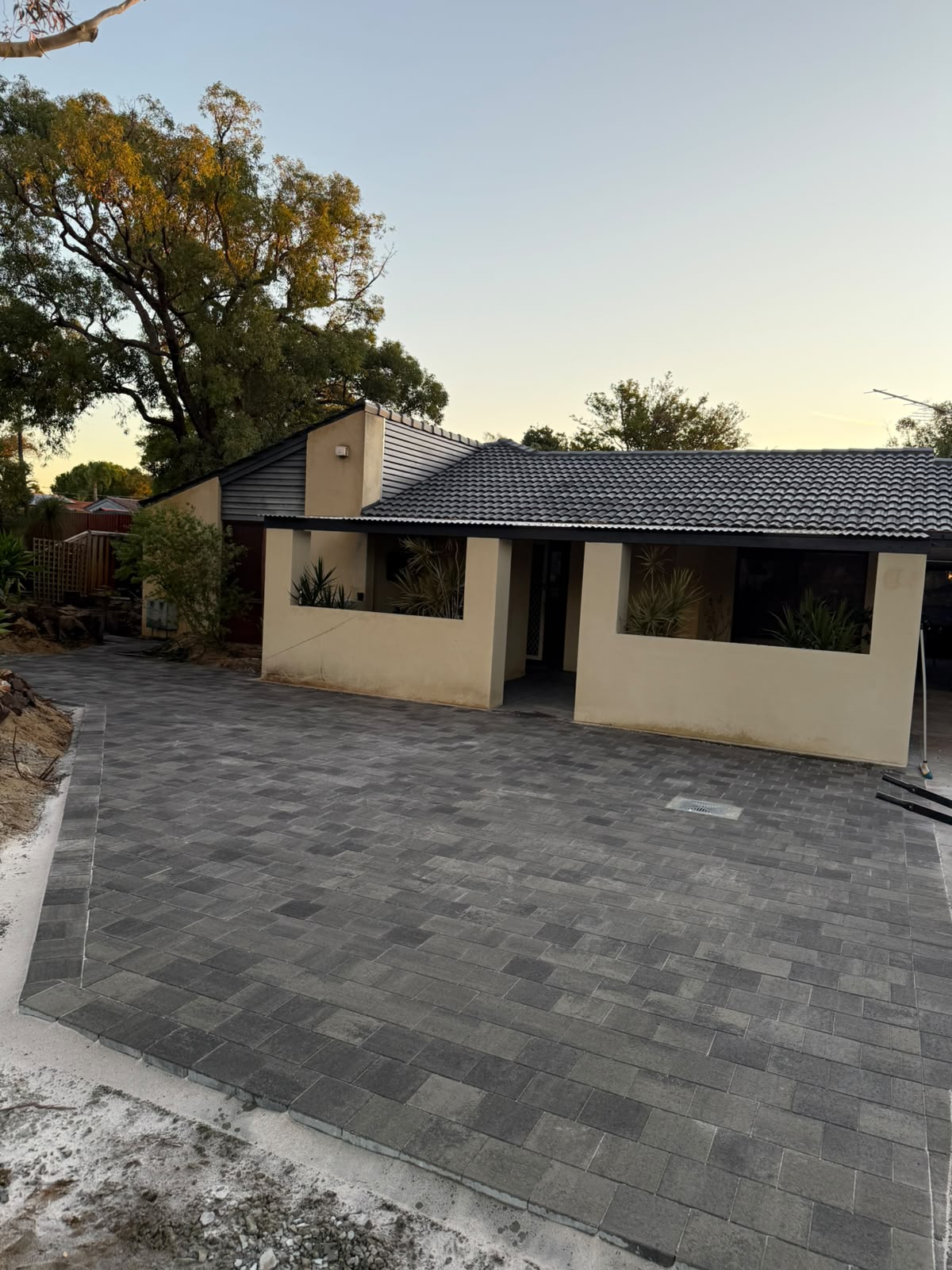 Grey concrete pavers laid across a driveway and forecourt at dusk, Perth